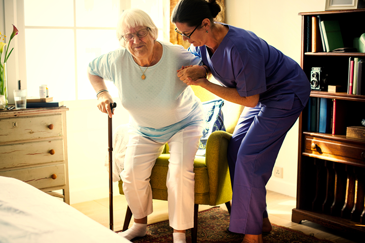 Female nurse helping elderly woman stand up